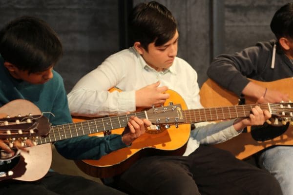 School based instruction 3 teenage kids playing guitar